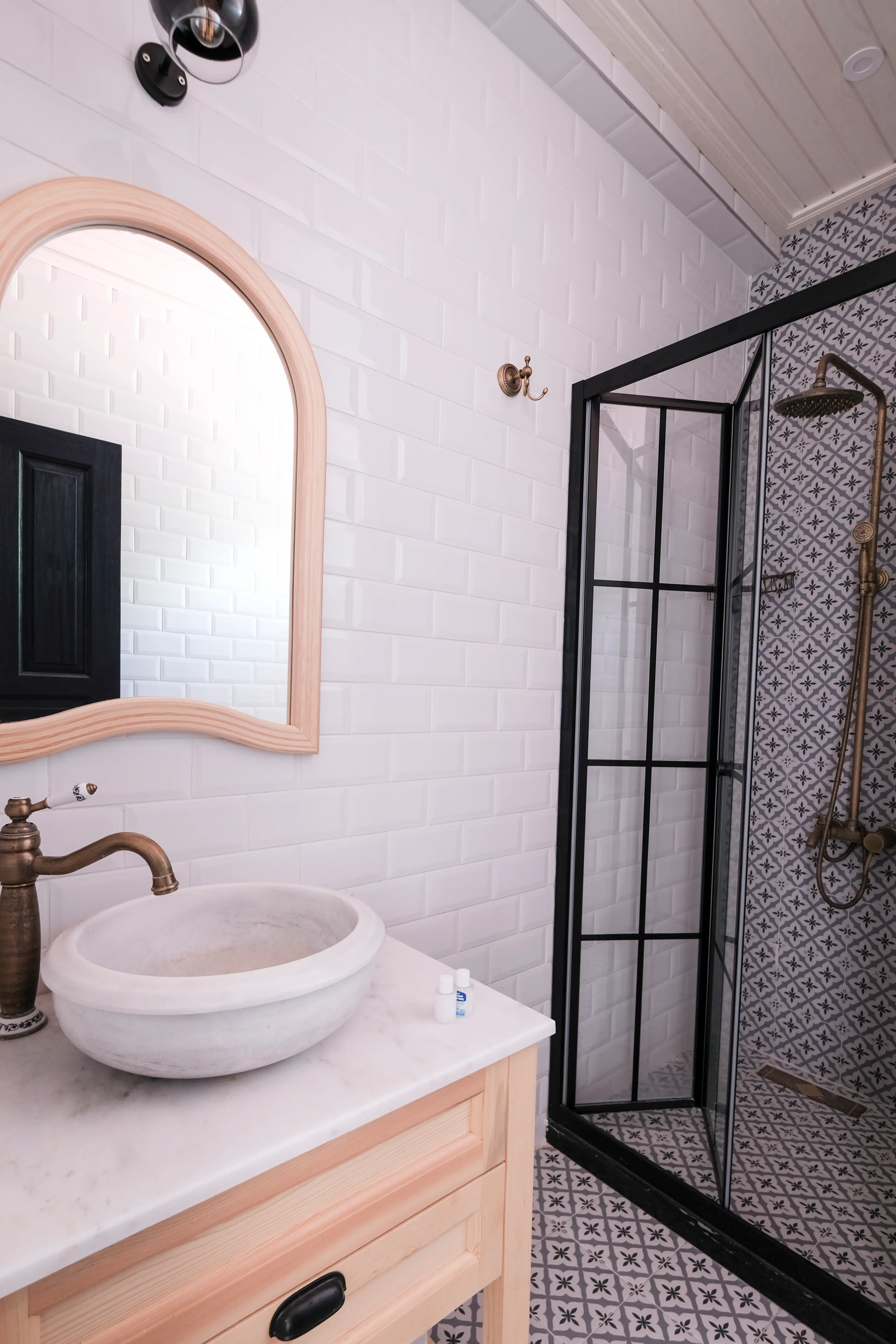Blue room bathroom with an arched mirror, stone basin and brass fixtures