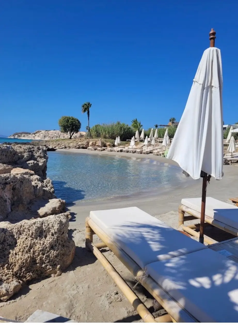 Sun loungers and a white parasol beside a sheltered sandy cove on the Cesme coast