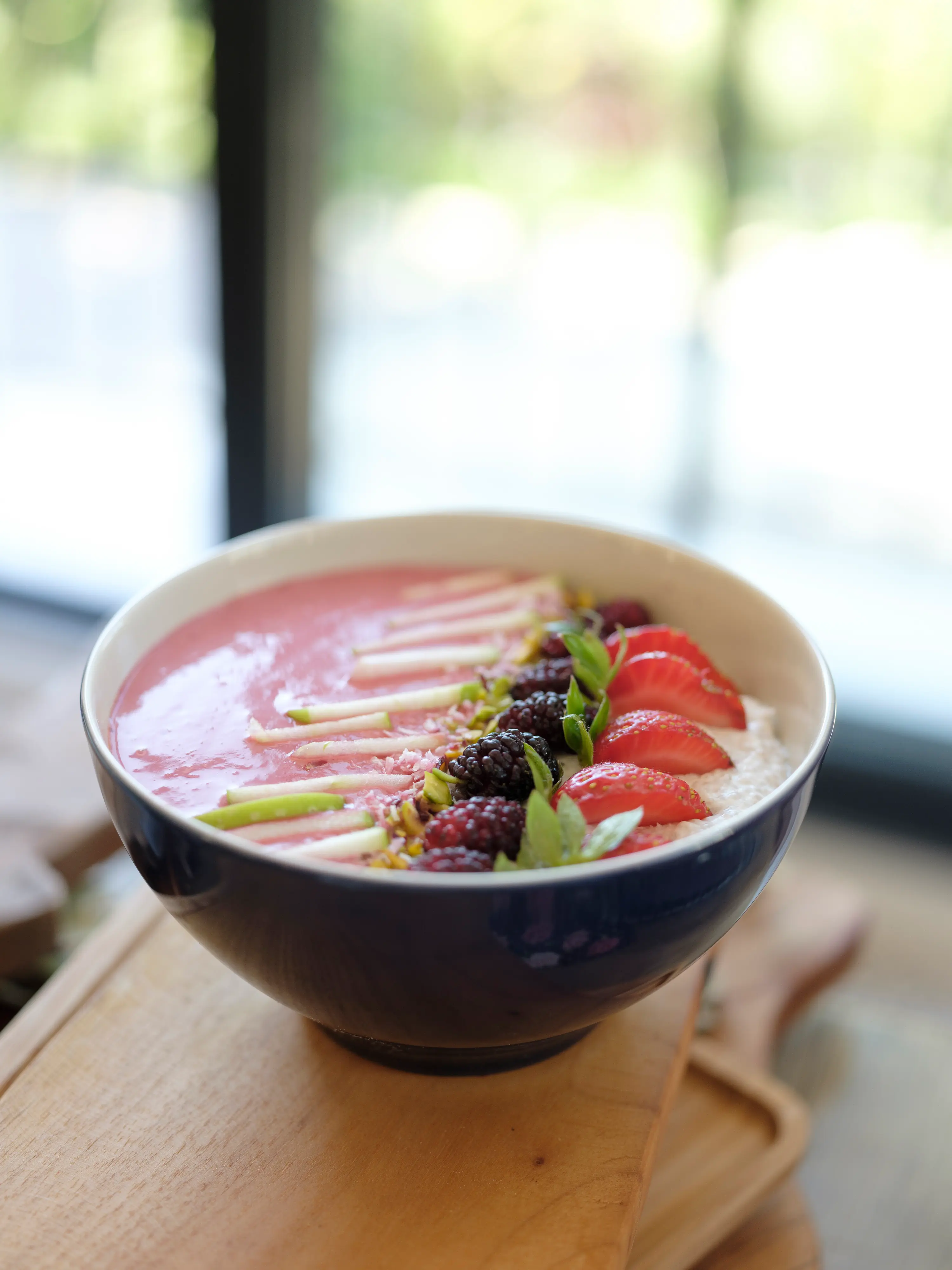 A pink smoothie bowl topped with berries and pistachio
