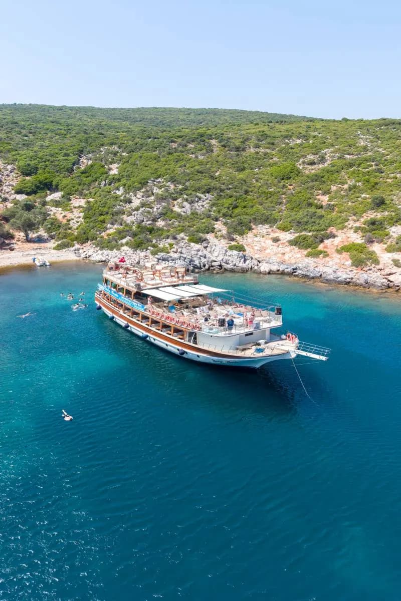The Lady Bente anchored in a turquoise Aegean bay near Çeşme, with swimmers in the water