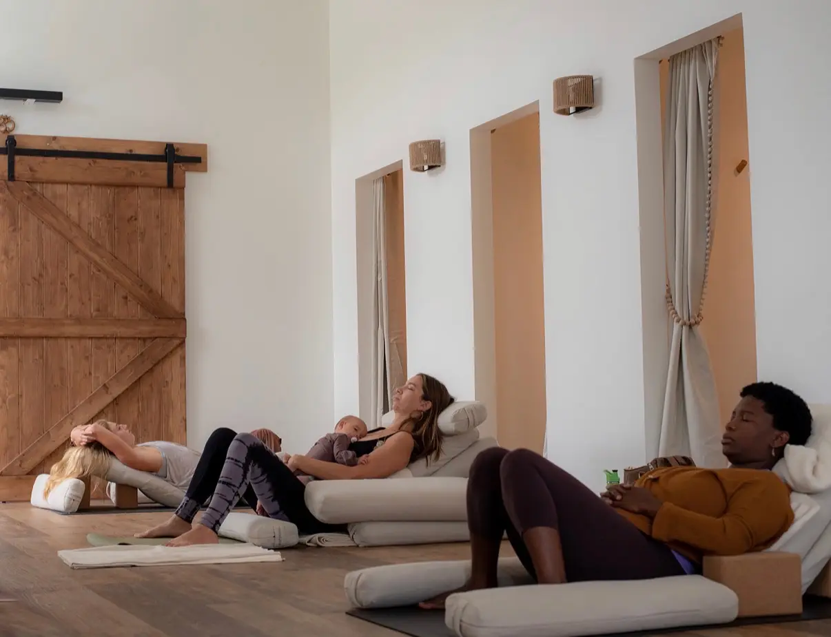 Prenatal yoga students resting in a supported reclining pose in the Moon Room